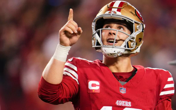 HD desktop wallpaper featuring a football player pointing upward, representing the NFL, sports, and the excitement of the Super Bowl.
