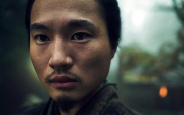 Close-up of a male character from Shogun 2024 TV show set as an HD desktop wallpaper with a blurred natural background.