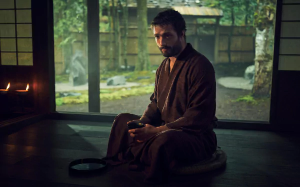 HD wallpaper featuring a contemplative scene from the TV show Shogun (2024) with a character in traditional attire sitting in a serene Japanese room overlooking a garden.