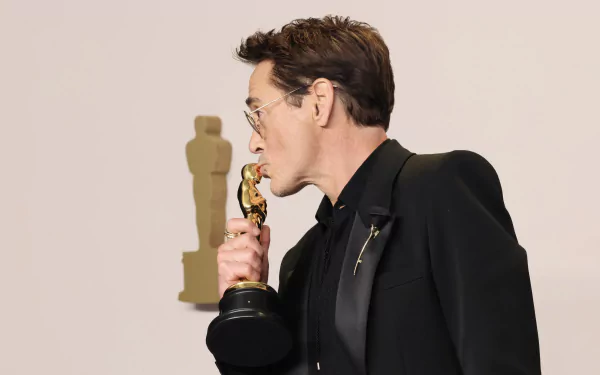 High-definition wallpaper featuring a person posing humorously with an Academy Award statue at the Oscars event.