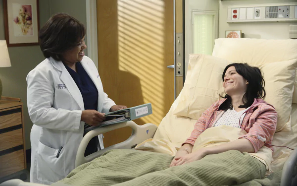 HD wallpaper of a Grey's Anatomy TV show scene featuring a doctor in a white coat speaking with a smiling patient in a hospital bed, suitable as a desktop background.