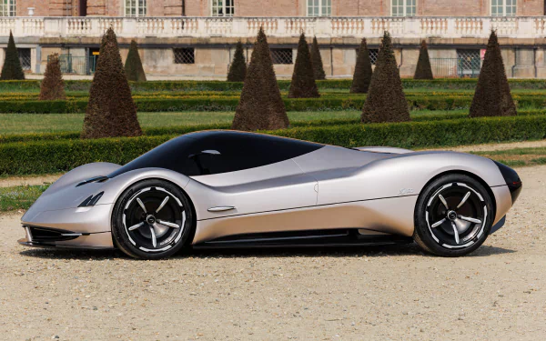 A sleek Pagani Alisea sports car parked on a gravel surface with manicured trees and a classic building in the background, suitable as a desktop wallpaper.