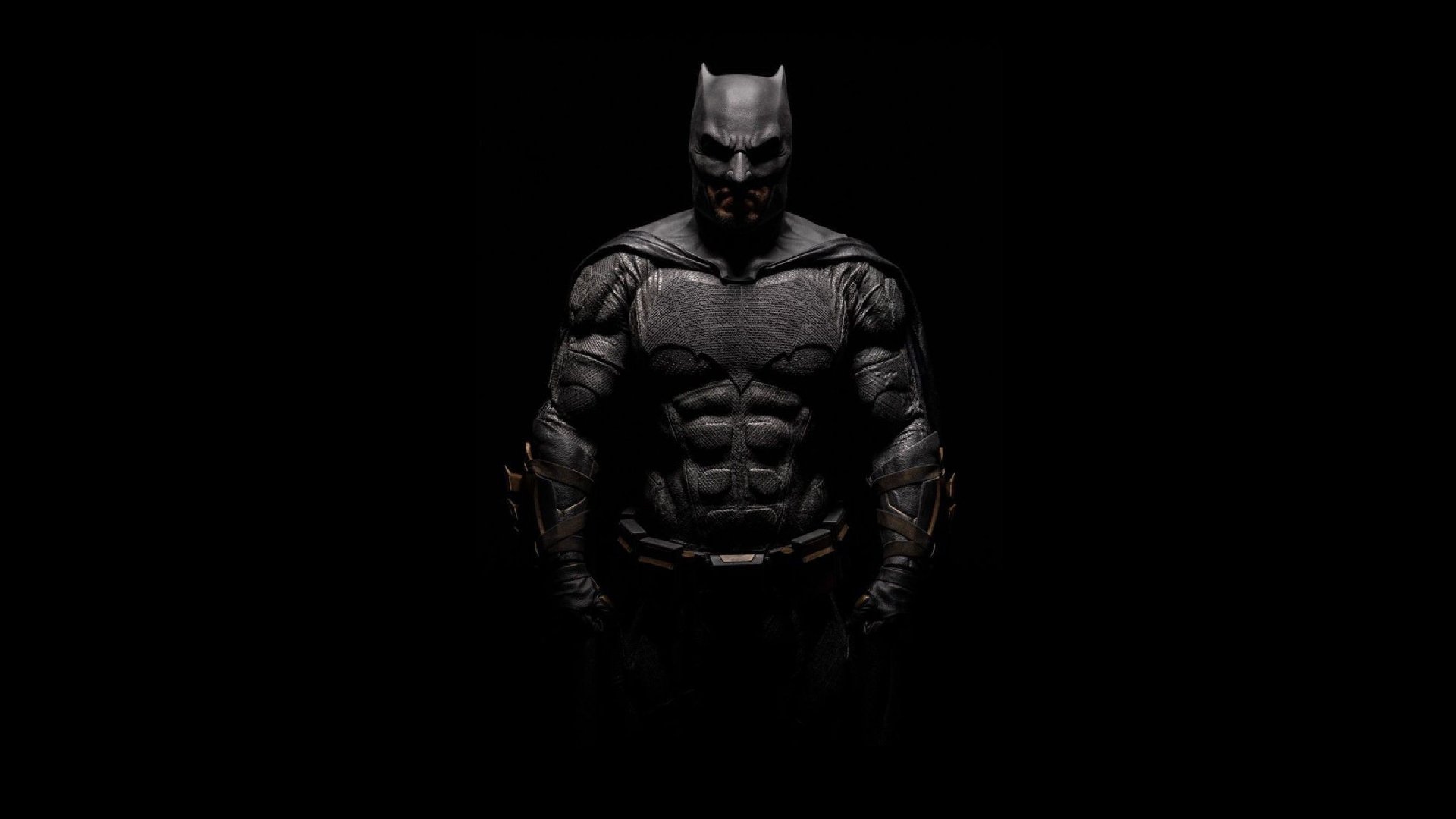 Shadowed armored Batman (Bruce Wayne) from DC Comics, Batman v Superman: Dawn of Justice aesthetic — muscular, helmeted figure centered on black HD PC desktop wallpaper/background.
