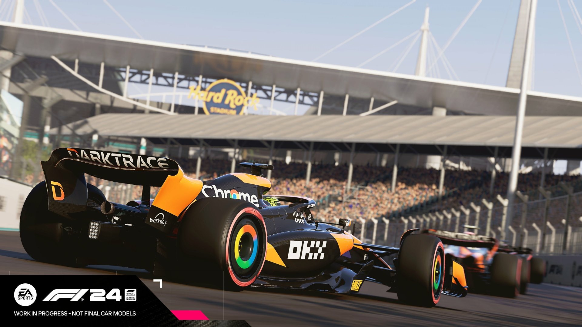 HD desktop wallpaper of F1 24 video game featuring high-speed Formula 1 cars racing on a track with a packed stadium in the background.