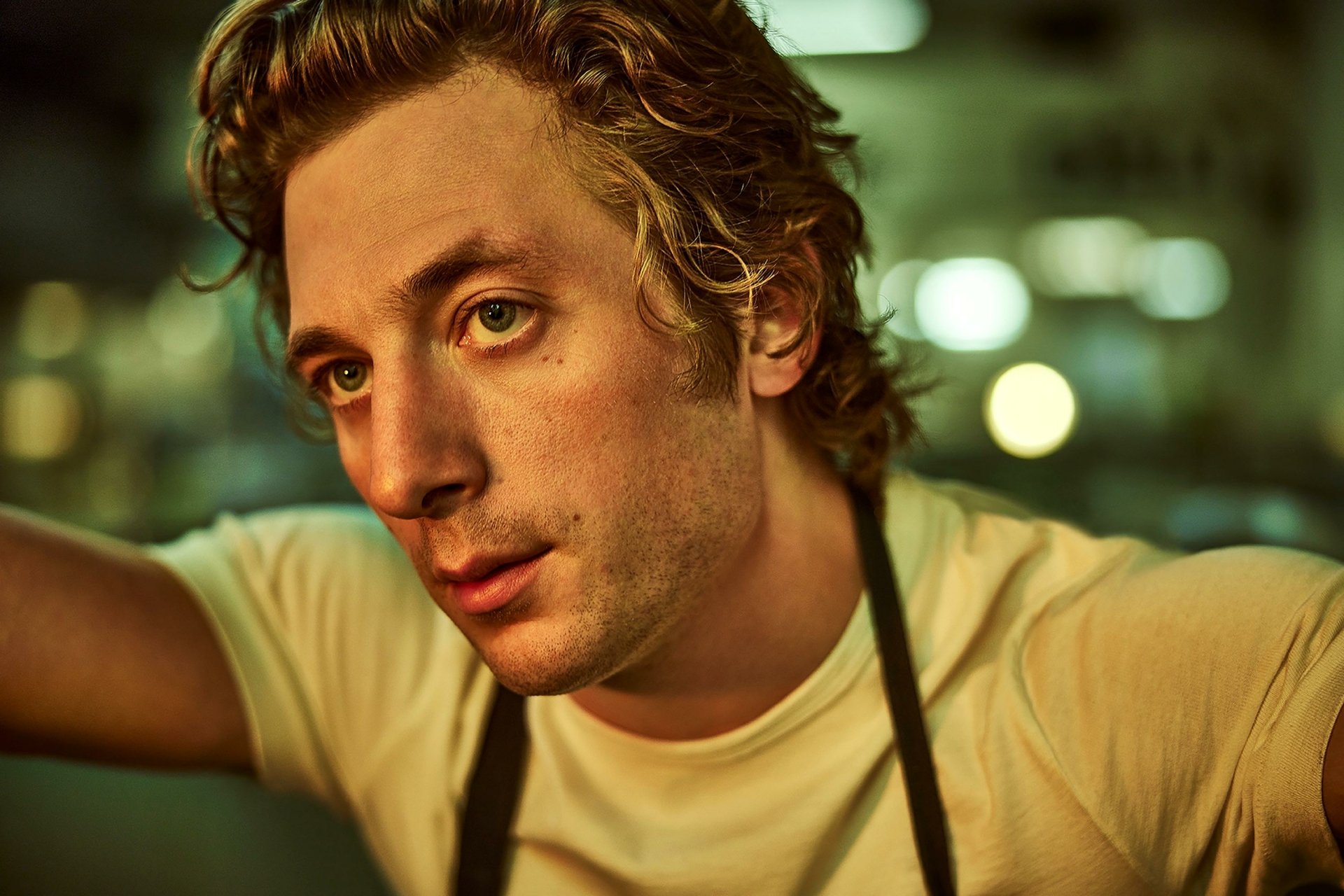 HD desktop wallpaper featuring Jeremy Allen White from the TV show The Bear, captured in a candid moment with a blurred background.