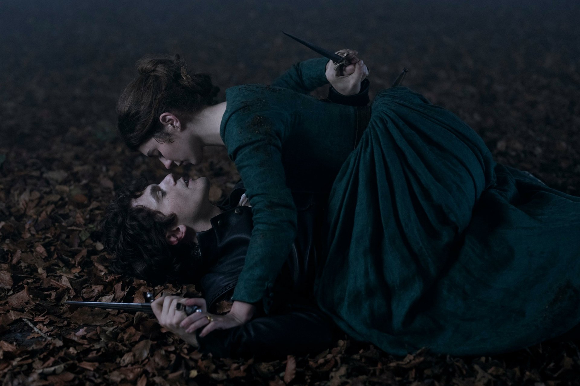A dramatic scene from the movie My Lady Jane, featuring two characters in an intense moment on a forest floor, serves as an HD desktop wallpaper and background.