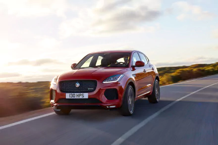 HD desktop wallpaper featuring a red Jaguar E-Pace car driving on an open road with a clear sky and scenic background.