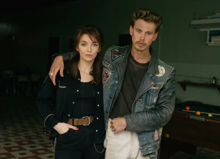 HD wallpaper from the movie The Bikeriders featuring Austin Butler and Jodie Comer in character, standing together in a casual setting.