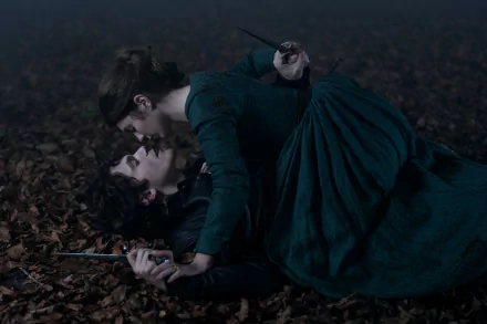 A dramatic scene from the movie My Lady Jane, featuring two characters in an intense moment on a forest floor, serves as an HD desktop wallpaper and background.