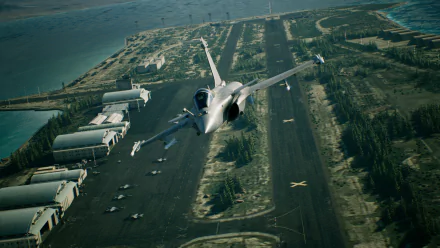 HD desktop wallpaper from Ace Combat 7: Skies Unknown featuring a fighter jet flying over a military airbase, capturing a realistic and dynamic aviation scene from the video game.