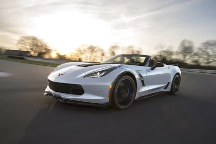 HD desktop wallpaper of a Chevrolet Corvette Carbon 65 Edition driving on a scenic road at sunset, showcasing its sleek design and dynamic performance.