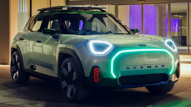 {{ HD wallpaper of a MINI Aceman vehicle parked, showcasing its distinctive front design with illuminated accents around the grille and headlights. 