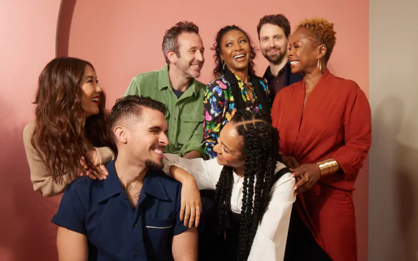 A group of joyous actors from the TV show The Big Door Prize posing together with smiles, set against a warm-toned background; suitable as an HD desktop wallpaper.