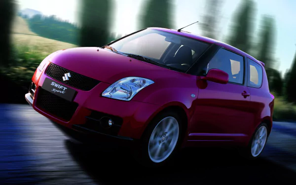 HD desktop wallpaper of a red Suzuki Swift Sport car driving on a road, with blurred greenery in the background.