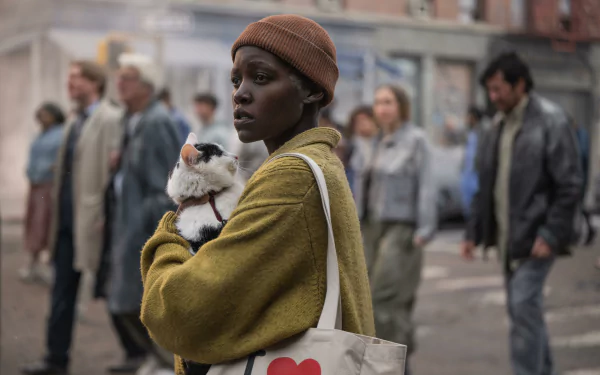 HD desktop wallpaper featuring Lupita Nyong'o in a scene from A Quiet Place: Day One. She is wearing a beanie and holding a stuffed animal on a busy urban street.