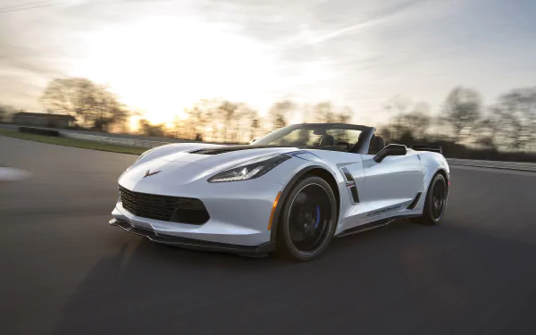 HD desktop wallpaper of a Chevrolet Corvette Carbon 65 Edition driving on a scenic road at sunset, showcasing its sleek design and dynamic performance.