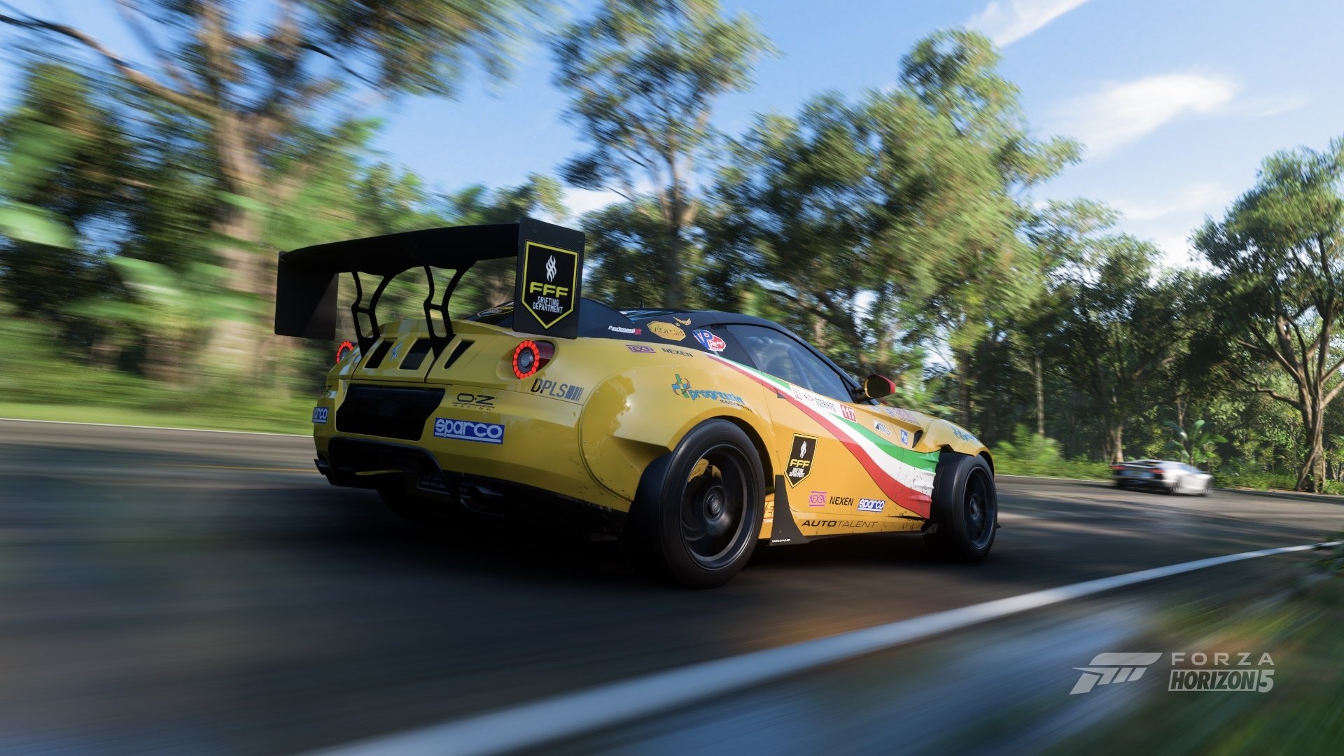 HD PC desktop wallpaper featuring a yellow Ferrari race car speeding on a tree-lined track under a clear sky.