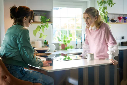 Two women converse intently in a bright kitchen, with plants and modern decor around them. This image captures a moment from the TV show A Good Girl's Guide to Murder.