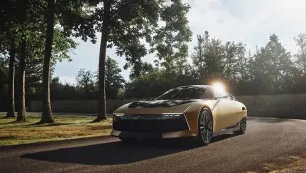 A sleek DS SM Tribute car is illuminated by sunlight as it drives along a tree-lined path, showcasing its modern design in this stunning 4K Ultra HD wallpaper.