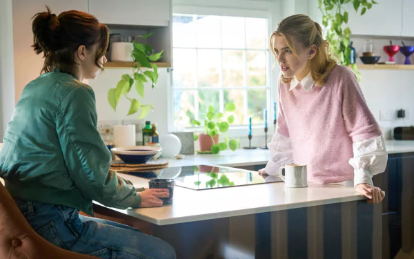 Two women converse intently in a bright kitchen, with plants and modern decor around them. This image captures a moment from the TV show A Good Girl's Guide to Murder.