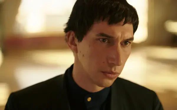 Adam Driver stars in the upcoming movie Megalopolis (2024). The image features him in a striking pose, set against a soft, blurred background.