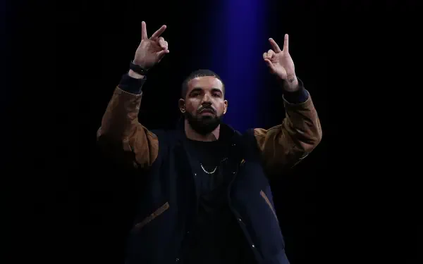 A striking HD wallpaper featuring rapper Drake performing with hand gestures, showcasing his dynamic stage presence and influence in the music industry.