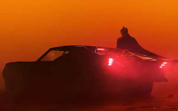 Silhouette of Batman standing near a sleek car with glowing taillights against a vibrant orange sky, captured in 4K Ultra HD for a dramatic PC desktop wallpaper.