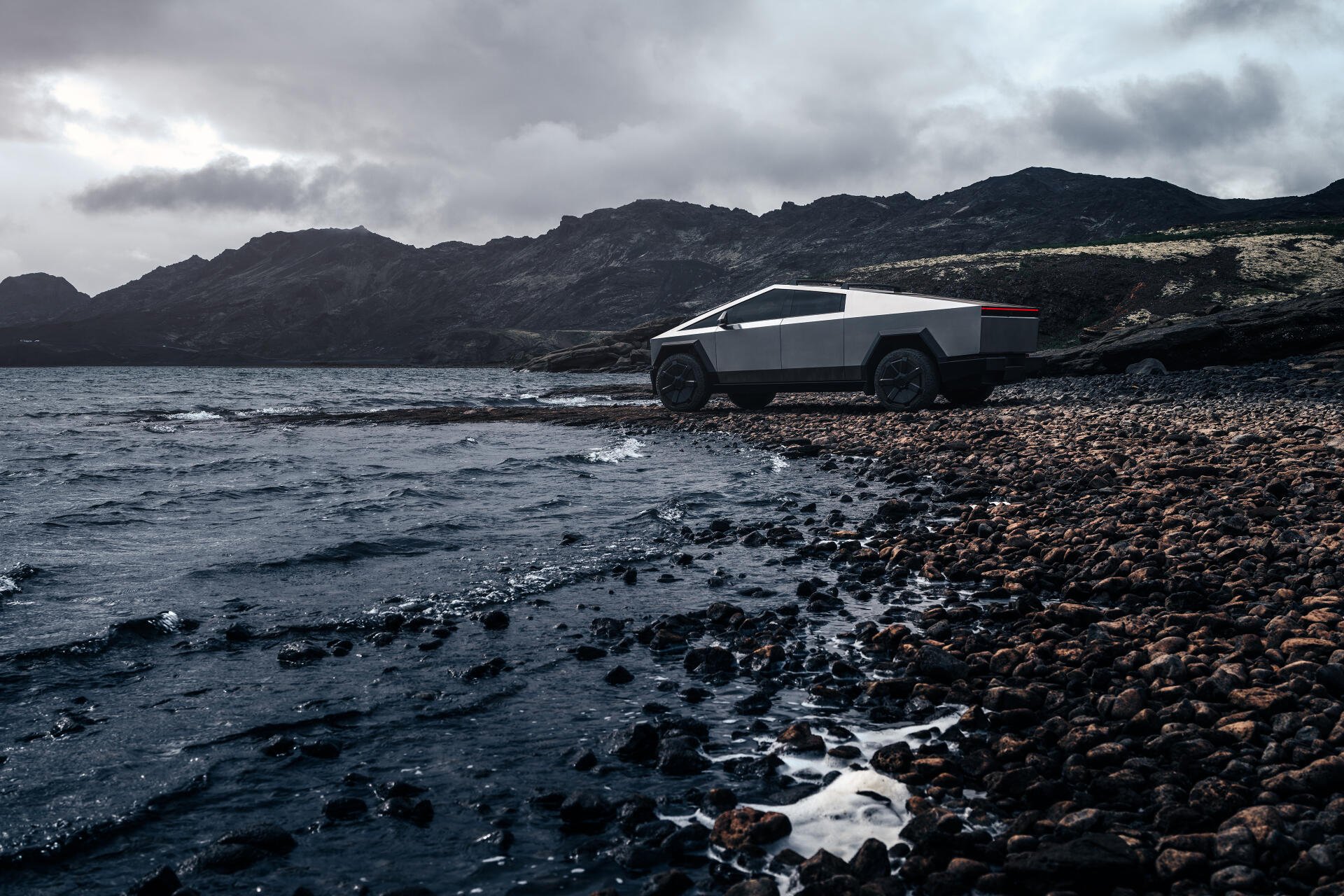 A sleek Tesla Cybertruck parked by the shore, surrounded by rugged rocks and a dramatic landscape, captured in stunning 4K Ultra HD resolution.