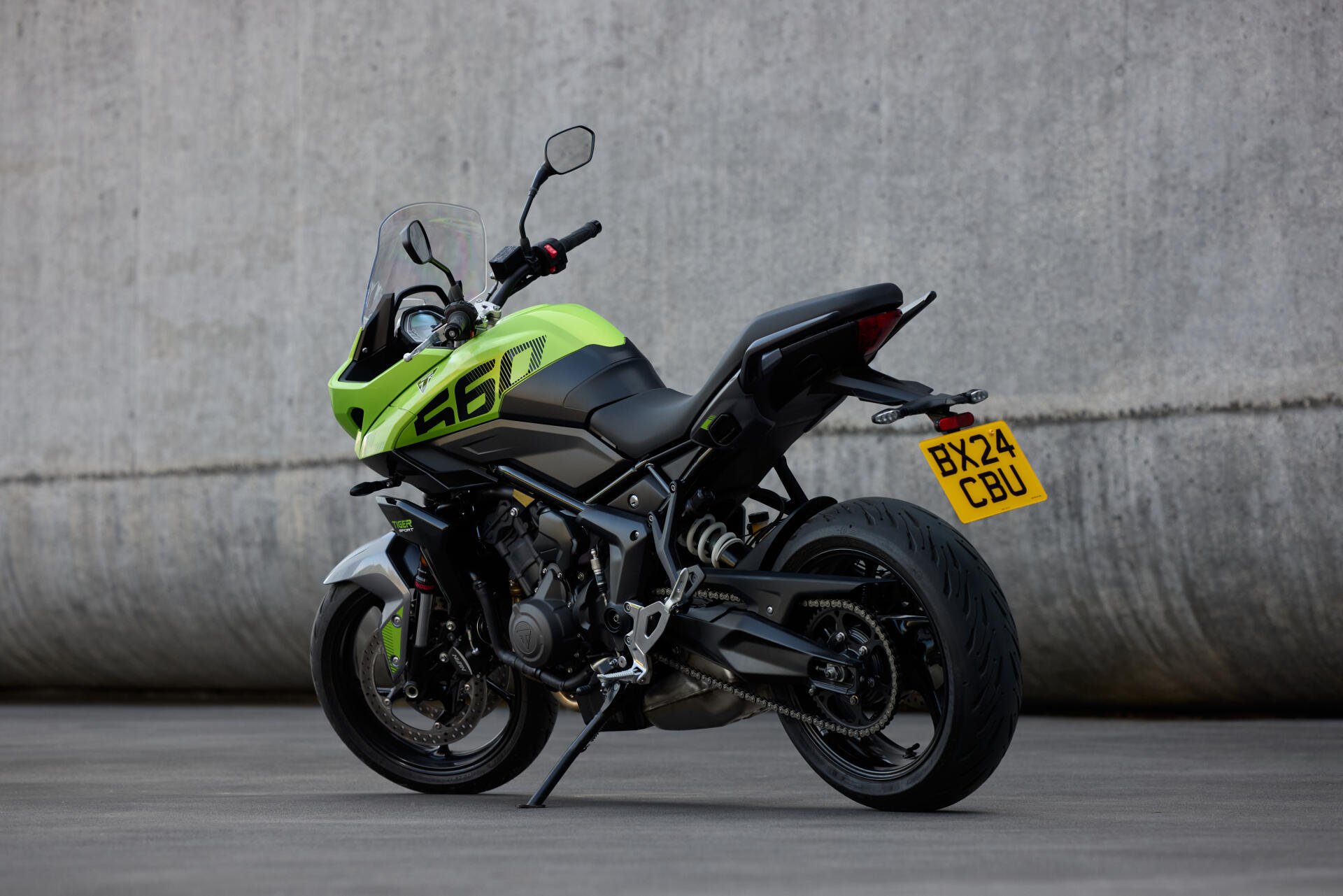 A Triumph Tiger Sport 660 motorcycle in vibrant yellow and black against a concrete wall, captured in 4K Ultra HD as a PC desktop wallpaper background.