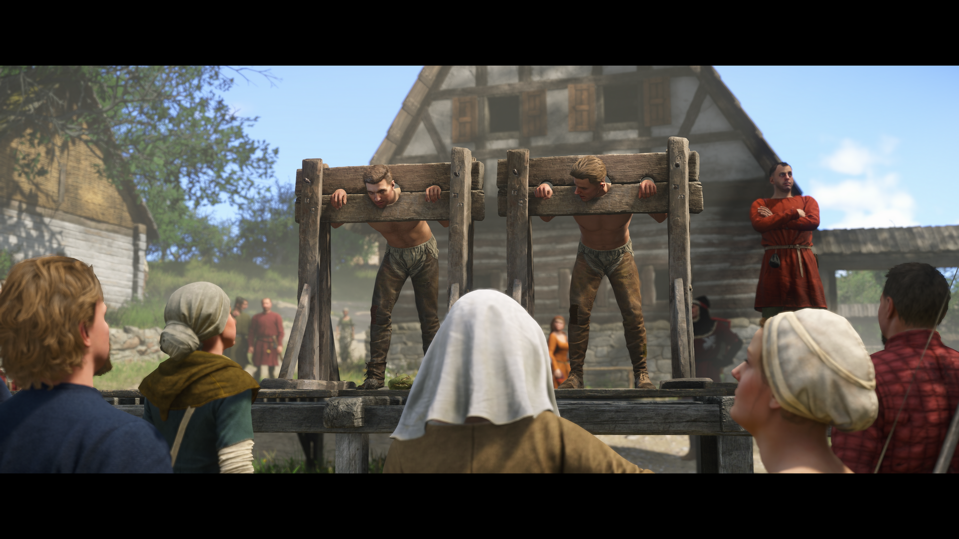 A captivating HD wallpaper from Kingdom Come: Deliverance II, depicting a medieval scene with townsfolk gathered around two individuals in stocks, under a clear blue sky.