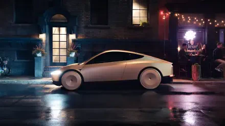 A sleek white Tesla robotaxi, featuring a futuristic design, parked on a rain-soaked street illuminated by warm lights from a nearby establishment.