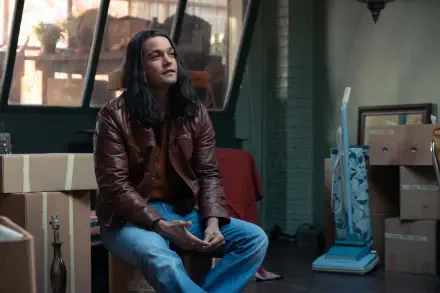 A scene from the movie *Woman of the Hour*, featuring a contemplative man in a leather jacket, surrounded by boxes in a sunlit, artistic space. 4K Ultra HD desktop wallpaper.