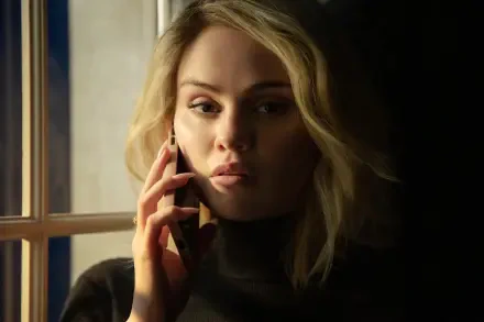 A captivating 4K Ultra HD wallpaper featuring Emilia Pérez, portrayed by Selena Gomez, deeply engaged in a phone conversation by a window with dramatic lighting.