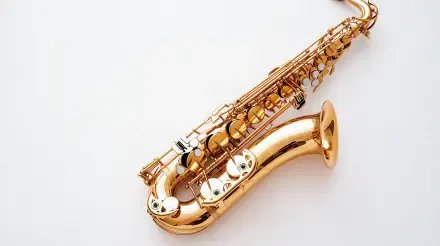 A close-up of a shiny gold saxophone on a clean white background, showcasing the intricate details of this musical instrument. This 4K Ultra HD image serves as a striking desktop wallpaper.