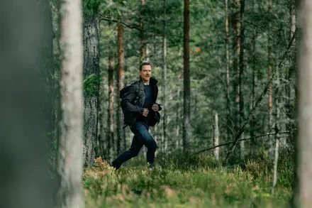 A scene from the TV show The Agency, featuring Michael Fassbender running through a lush green forest, captured in stunning 4K Ultra HD.