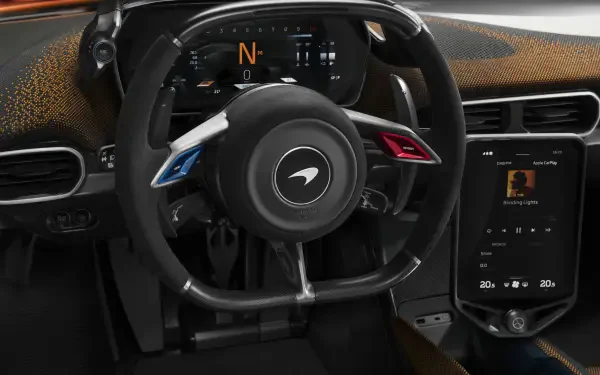 Detailed interior view of a McLaren W1, showcasing the sleek steering wheel and advanced digital display. An 8K Ultra HD desktop wallpaper highlighting automotive design.