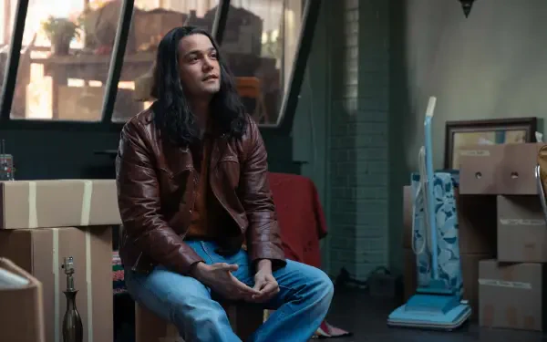 A scene from the movie *Woman of the Hour*, featuring a contemplative man in a leather jacket, surrounded by boxes in a sunlit, artistic space. 4K Ultra HD desktop wallpaper.