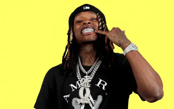A vibrant HD wallpaper featuring rapper King Von, showcasing his signature confident pose, adorned with flashy jewelry against a bright yellow background.