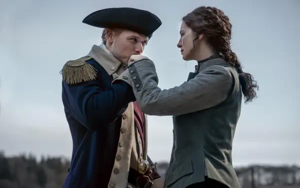 A dramatic moment from the TV show Outlander, featuring two characters in historical attire, capturing a sense of tension and connection against a muted outdoor backdrop.