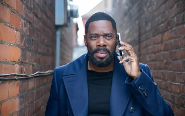 Colman Domingo, starring in the TV show The Madness, is featured in this HD wallpaper, captured in a narrow alley while talking on his phone.
