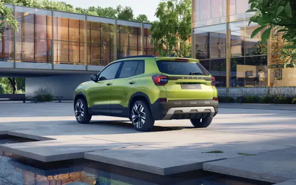 A vibrant green Škoda Kylaq parked outside a modern building, surrounded by lush greenery and a tranquil water feature. Captured in stunning 4K Ultra HD.