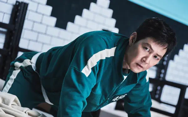 Lee Jung-jae in a scene from the TV show Squid Game, portrayed in a dynamic pose. This HD wallpaper captures the intensity of the character against a stylized background.