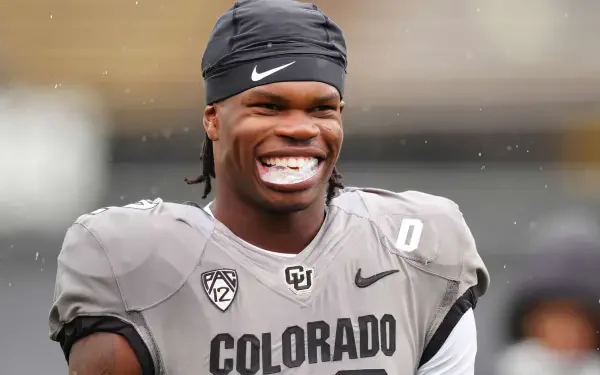 Travis Hunter smiles while wearing a Colorado Buffaloes football uniform, captured in this vibrant HD wallpaper showcasing his athletic spirit and team pride.