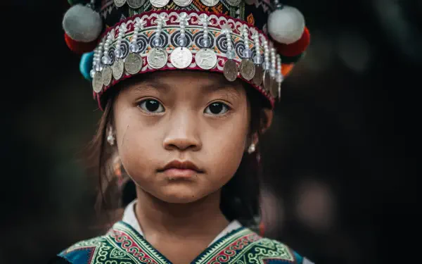 5K Ultra HD PC desktop wallpaper: portrait of a woman/girl wearing an ornate traditional headdress and embroidered garment, gazing directly at the viewer with a calm, serious expression.