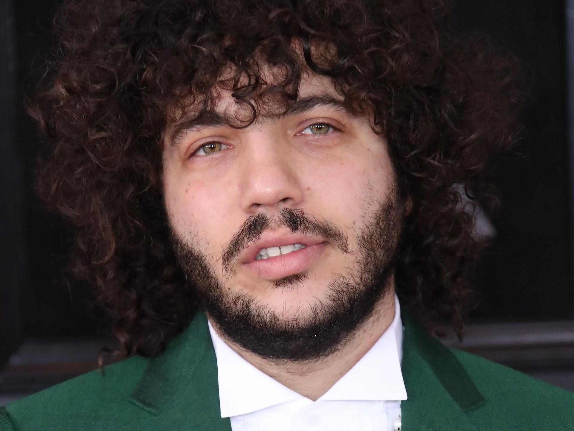 Close-up of Benny Blanco, featuring his curly hair and beard, set against a neutral background. The image serves as a vibrant HD PC desktop wallpaper and background.