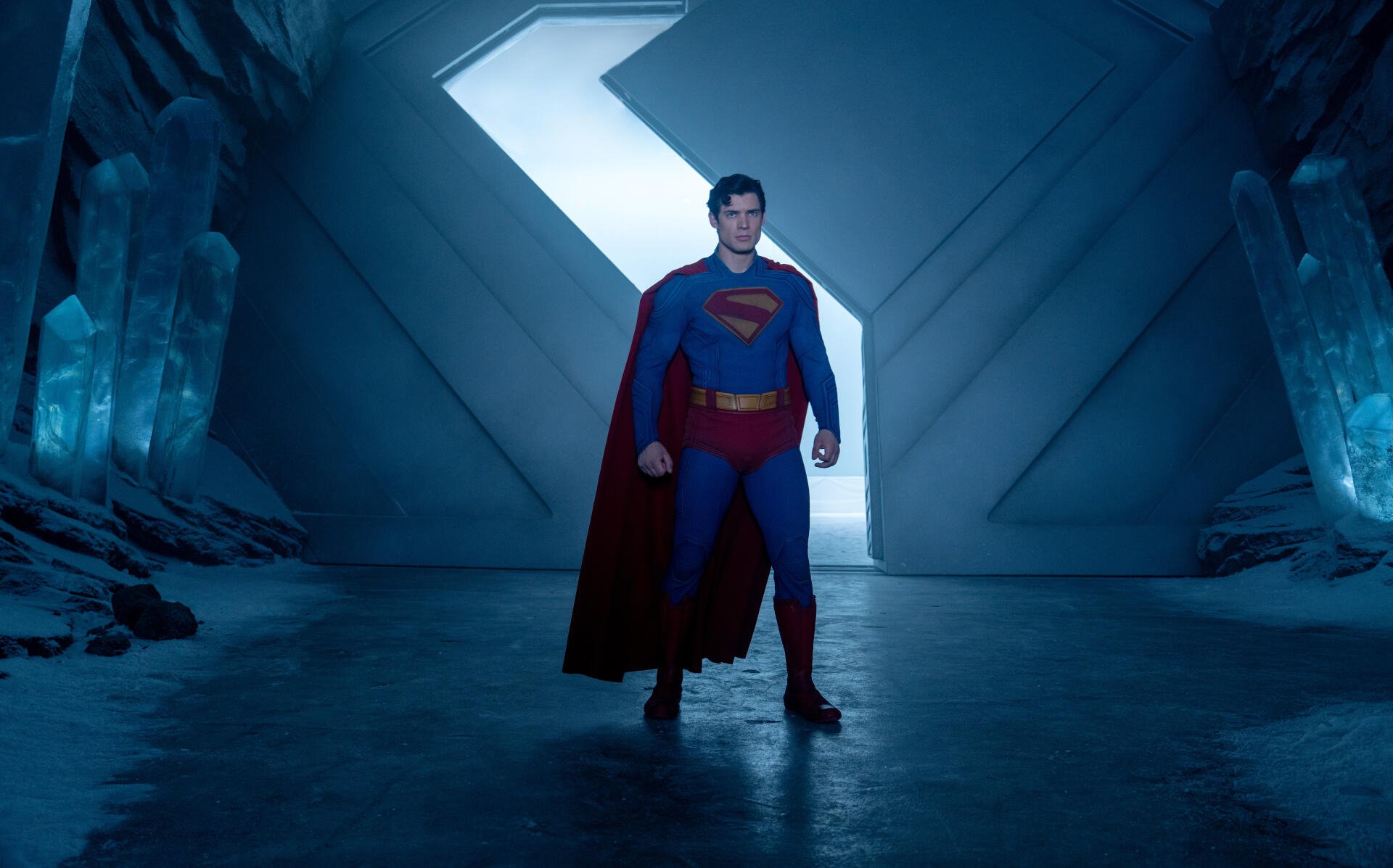 Superman stands in a glowing ice cavern, depicted in a detailed 8K Ultra HD PC desktop wallpaper from Superman (2025).
