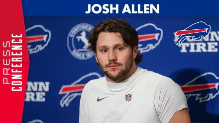 Josh Allen, quarterback for the Buffalo Bills, poses during a press conference, set against a bold background featuring the team’s colors and logos. HD desktop wallpaper.