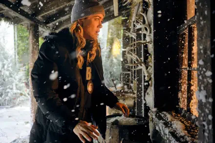 Melissa Roxburgh in a snowy scene from the TV show The Hunting Party (2025), wearing a beanie and coat, engaging with a cozy fireplace backdrop. HD wallpaper for desktop backgrounds.