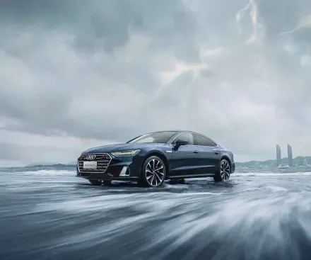 Dark Audi car on a windswept icy shore beneath moody clouds — 4K Ultra HD PC desktop wallpaper and background highlighting the sedan's sharp profile.