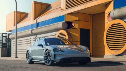 A sleek Porsche Taycan 4S Cross Turismo parked in front of a vibrant, modern building, showcasing its dynamic design in stunning 4K Ultra HD quality.